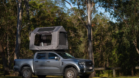 Ford Ranger in full side profile with the grey Often rooftop tent deployed on the roof rack, parked among eucalypts, showing the total height of the setup