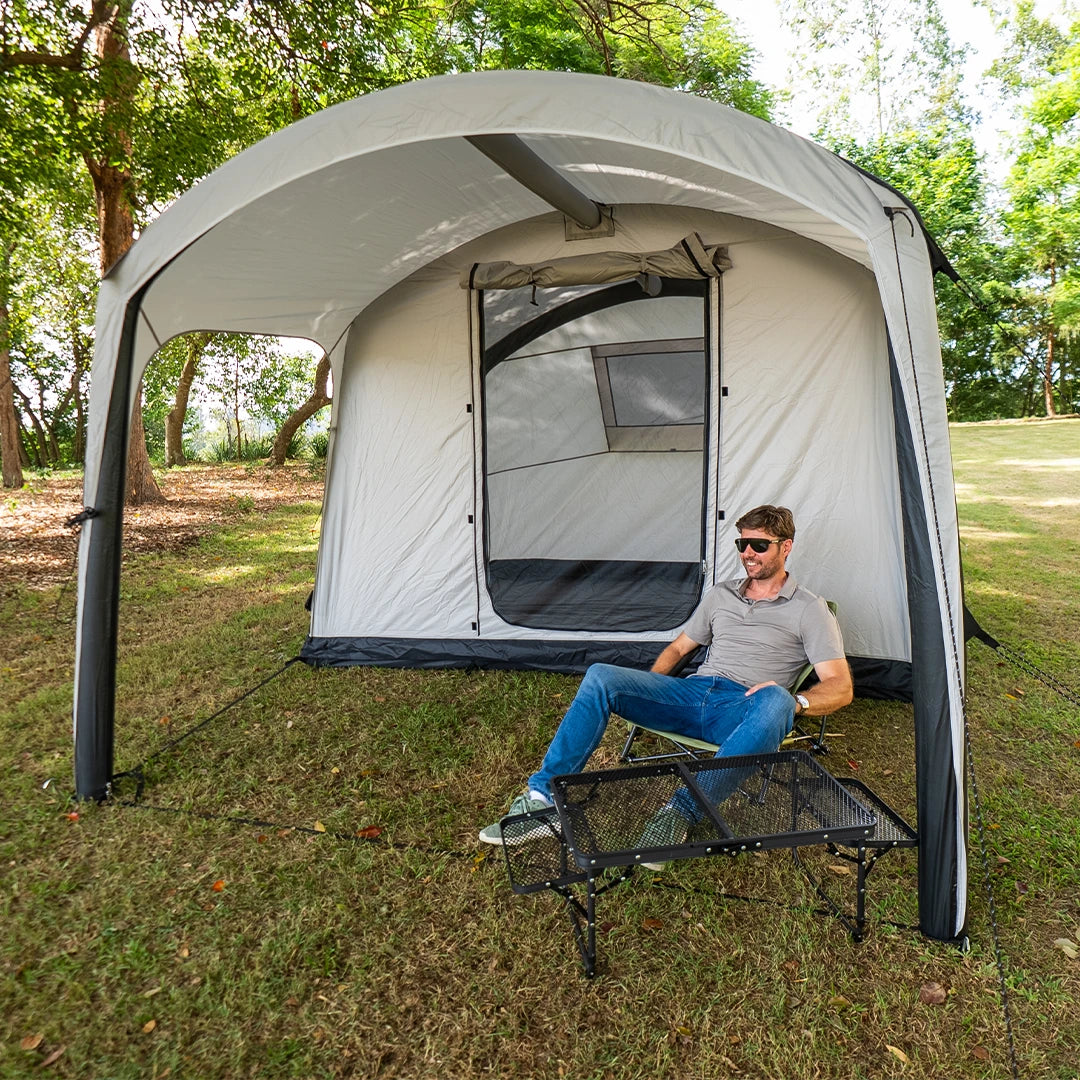 Camper resting on a stretcher under the Often Sunday canopy awning at a shaded grass campsite
