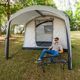 Camper resting on a stretcher under the Often Sunday canopy awning at a shaded grass campsite