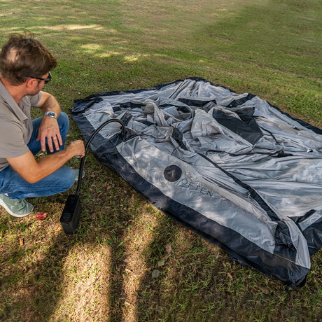 Inflating the Often Sunday with a hand pump, tent laid flat on grass before pitching